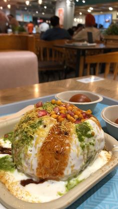 a plate with food on it sitting on a table in a restaurant next to bowls of dipping sauces