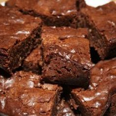 chocolate brownies stacked on top of each other on a white plate with a wooden table in the background