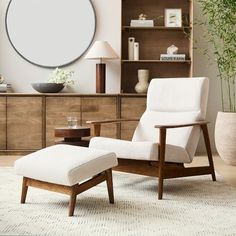 a white chair and ottoman in a living room with a large round mirror on the wall