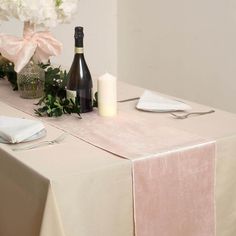 a table topped with a bottle of wine next to a vase filled with white flowers