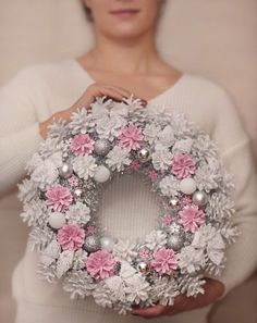 a woman holding a wreath with pink and white flowers