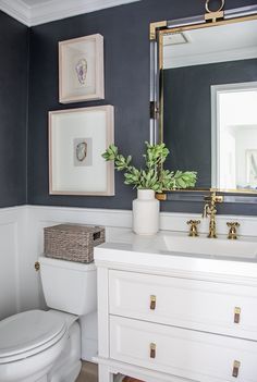 the bathroom is decorated in navy and white with gold accents, including framed pictures on the wall