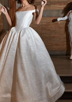 a woman in a white dress is standing on some steps