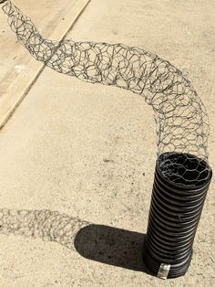 there is a wire fence that has been placed on top of the pole and it's shadow cast onto the ground