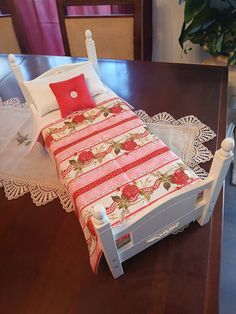 a doll bed with red and white sheets on it