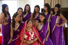 a bride and her bridal party posing for a photo in their purple sari