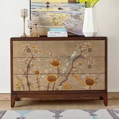 a dresser with sunflowers painted on the side and flowers in vase next to it