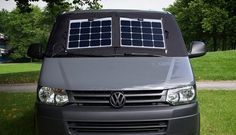 a van with solar panels on the roof is parked in front of some trees and grass