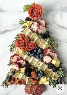 a christmas tree made out of cheese, berries and other foods on a marble table