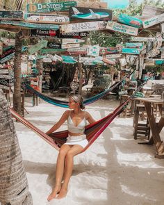 a woman sitting in a hammock with many signs on the wall behind her