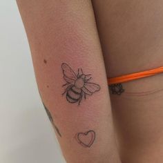 a woman's thigh with a tattoo of a bee and heart on the side