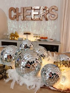 several disco balls on a table in front of a wall with the word cheers spelled out