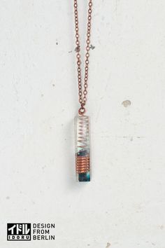 a necklace with a small glass tube hanging from it's side on a chain