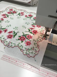 a machine is cutting fabric with red flowers on it and measuring the area for sewing