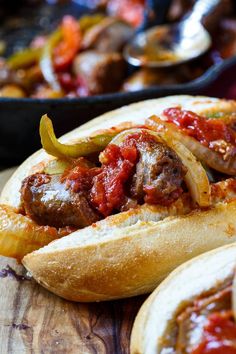 some very tasty looking hot dogs in buns on a wooden table with other food items