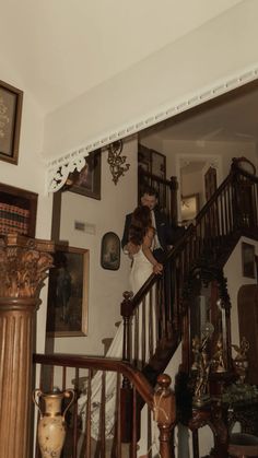 a bride and groom are standing on the stairs in their home, looking at each other