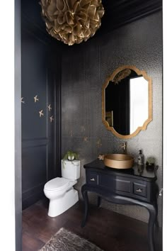 a bathroom with a black vanity, gold accents and a round mirror on the wall