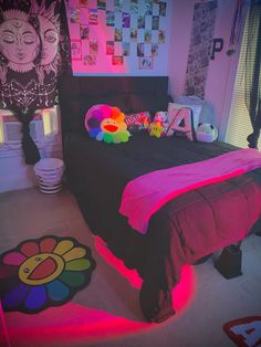 a bedroom with pink and black bedding, posters on the wall and colorful rugs