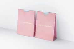 two pink shopping bags with the words the bathrooms printed on them are standing next to each other