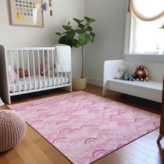 a baby's room with a pink rug and white crib