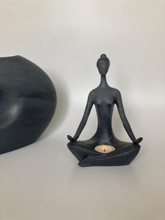 a candle is sitting in the shape of a buddha figure next to a black sculpture