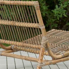 a wicker rocking chair sitting on top of a wooden floor next to a bush