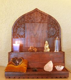 a wooden shrine with candles, rocks and other items sitting on the table next to it