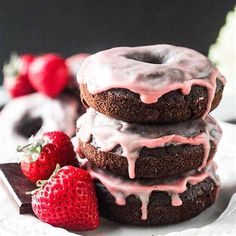 three chocolate donuts stacked on top of each other with icing and strawberries