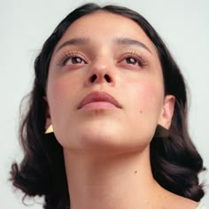 a close up of a woman with her eyes closed and one eye half closed, wearing gold earrings