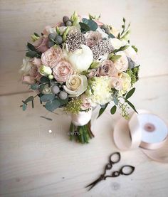 a bridal bouquet with scissors and tape on the table next to it, along with two rolls of toilet paper