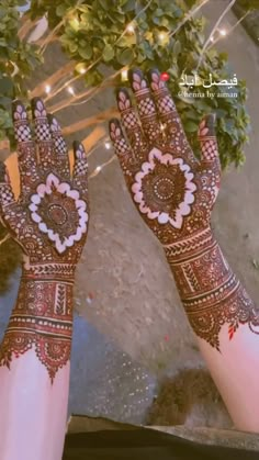 two hands with hendi designs on them and lights in the back ground behind them