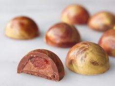 an assortment of fruits and chocolates on a white surface with one piece cut in half