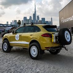 a yellow suv parked in front of a large city