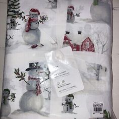 four snowmen on white sheets with red barn in the background