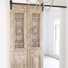 an old wooden door with pearls hanging from it's handlebars in a white room