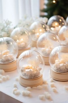 several snow globes are sitting on a table with white pom - poms