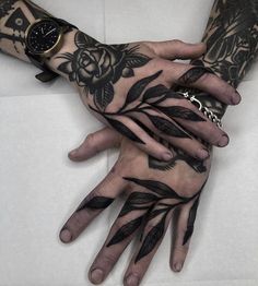 two hands that have tattoos on them, one has a watch and the other has flowers