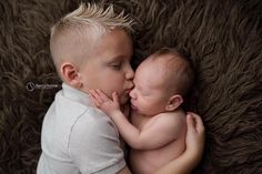 a couple of babies laying next to each other on top of a brown blanket together