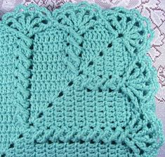 a green crocheted dishcloth sitting on top of a lace table cloth next to a white doily