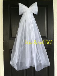 a white dress hanging on a door with a bow at the top and bottom part