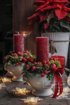 three red candles are sitting in white bowls with holly and pine cones on the table