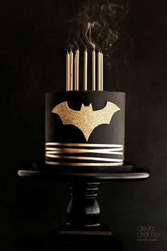 a black and gold batman cake with candles on top is featured in instagrams