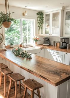 a kitchen with wooden counter tops and stools in front of a window that has plants growing on it