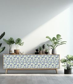 a white and blue cabinet with potted plants on it in front of a wall