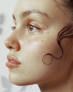 a woman with freckles on her face looking to the side while wearing earrings