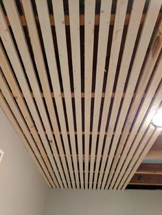 the ceiling is made out of wooden slats and has been stripped off with paint