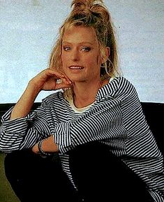 a woman sitting on top of a black couch next to a white and blue wall