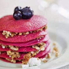 a stack of pancakes topped with blueberries and walnuts