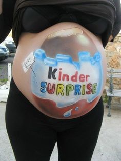 a pregnant belly with the words kinder surprise painted on it