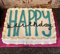 a birthday cake with the word happy on it and sprinkles in blue